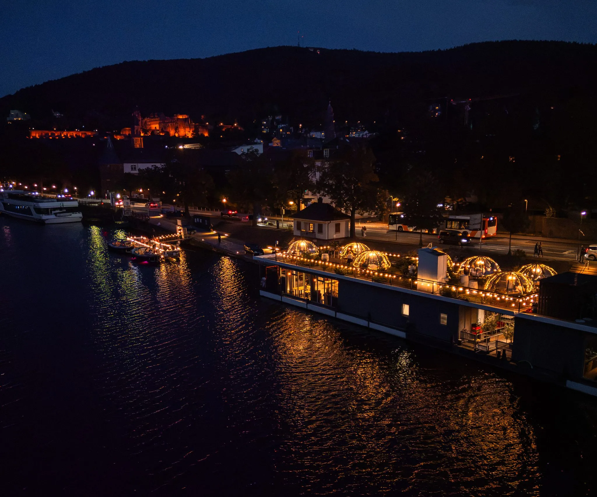 Pier IV bei Nacht mit leuchtenden Iglus am Neckar, beleuchtetes Schloss im Hintergrund