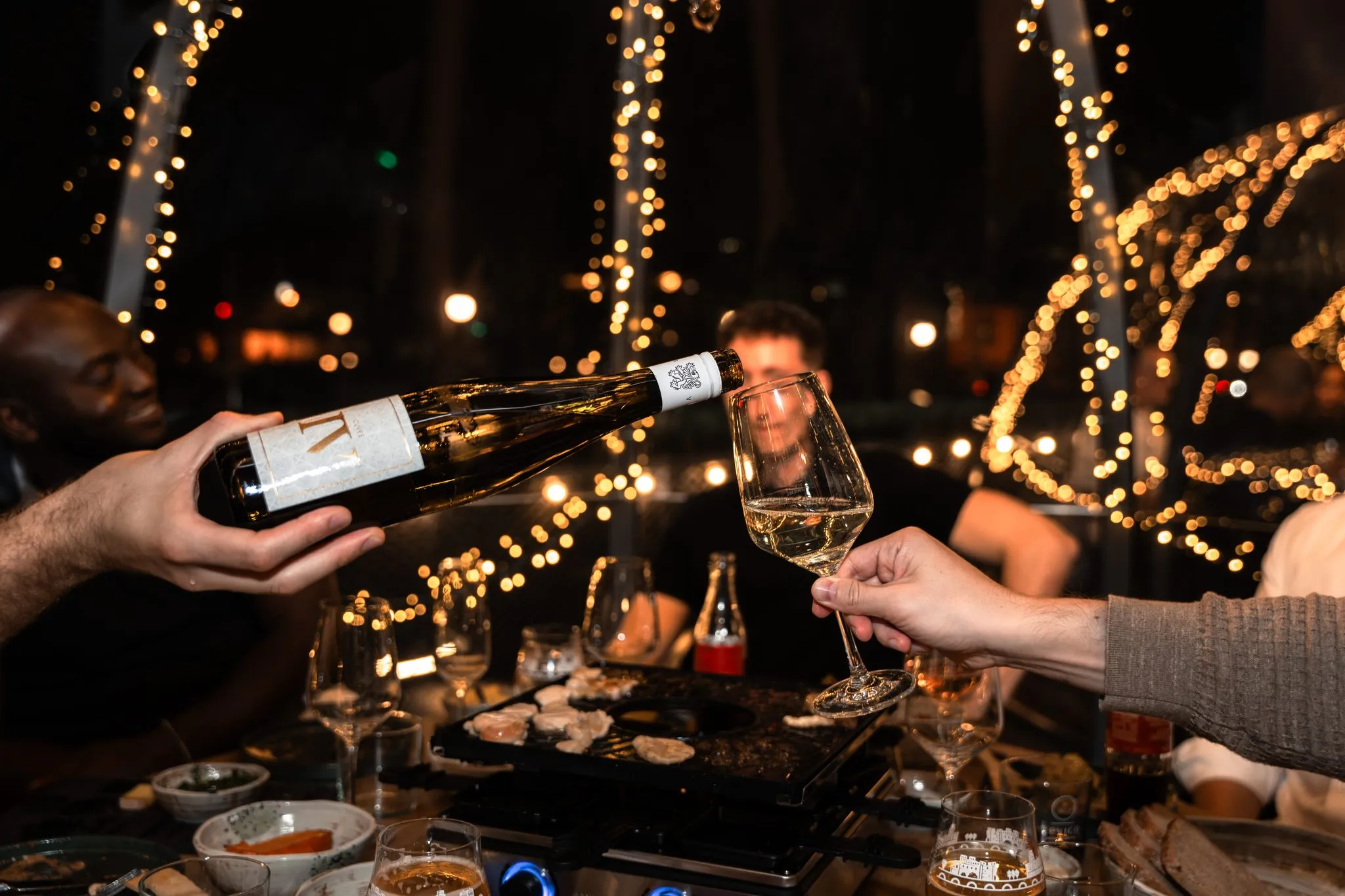 Wein wird im Iglu eingeschenkt, Lichterketten im Hintergrund